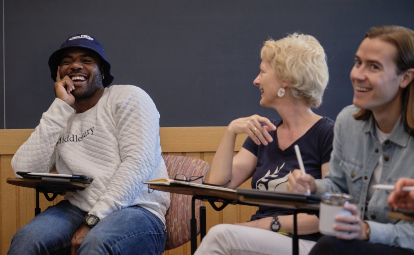 Students sit in class, laughing and smiling.
