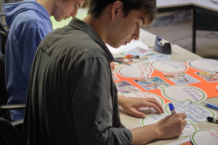 Students work on their Korean comic strips on a table.