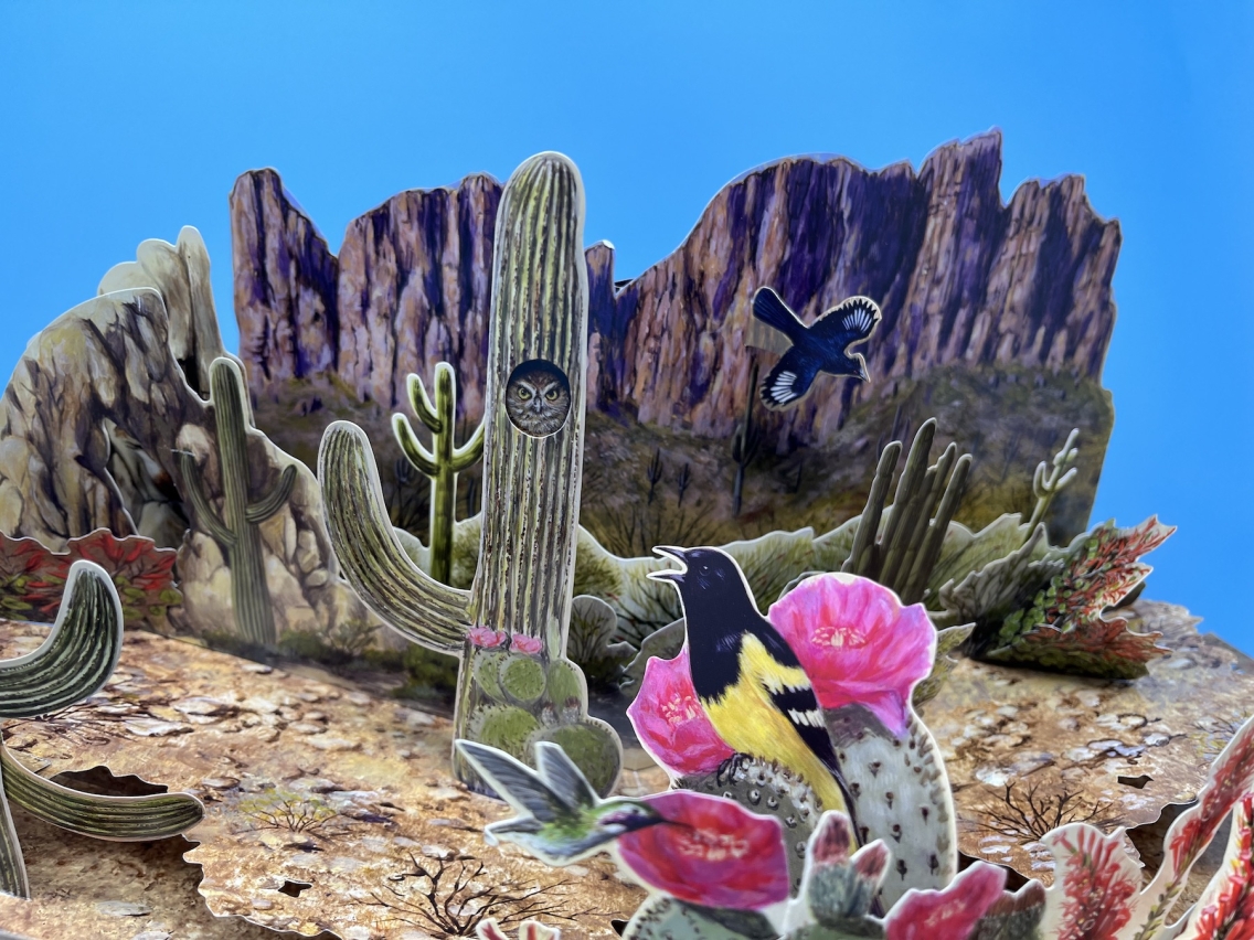 a pop-up book page with owls and cacti 