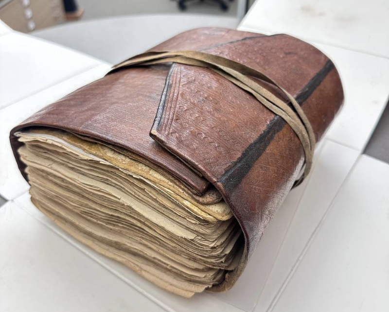 stacked pages of Quran bound up in a leather case resting on a desk