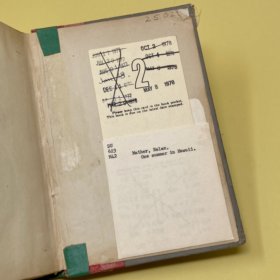book open to back cover with borrowing card of dated stamps in envelope