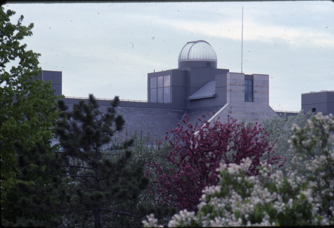 building with observatory against gray sky and flowering trees in foreground