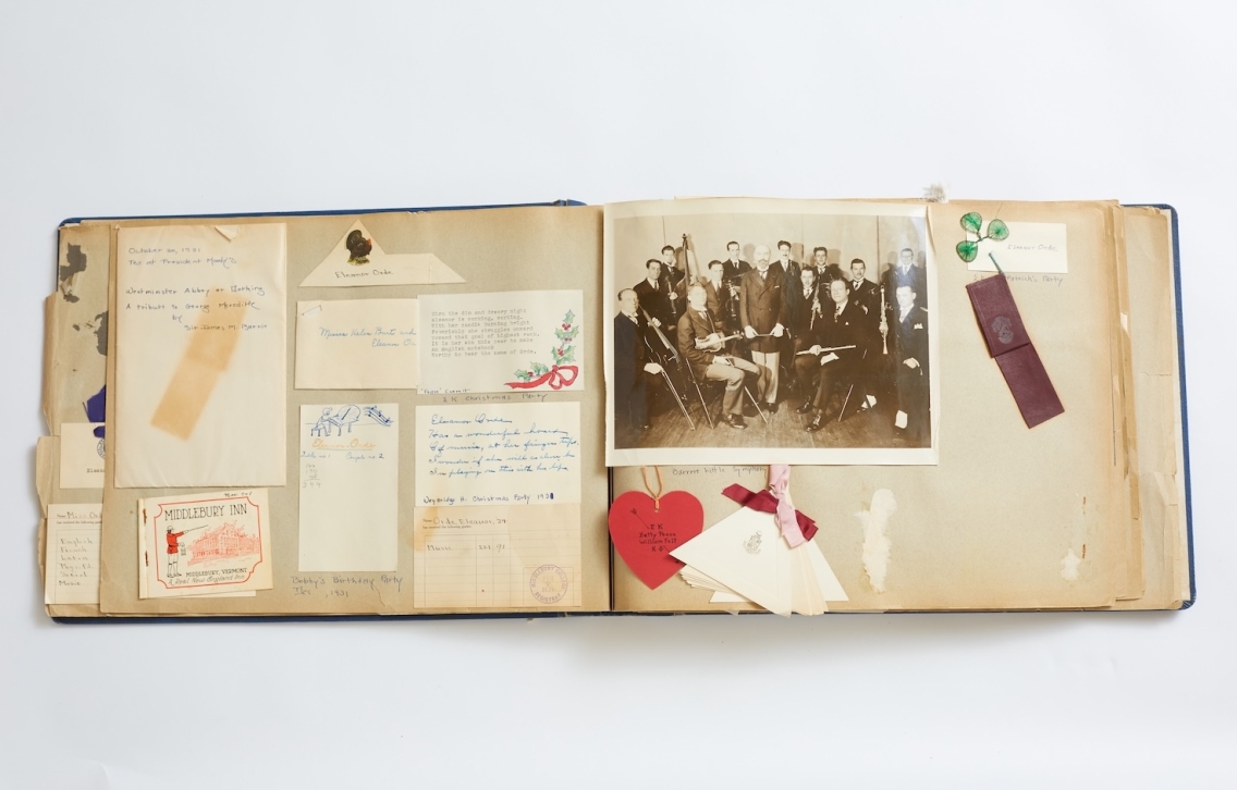 open scrapbook with group photo, letters, receipts, and labels