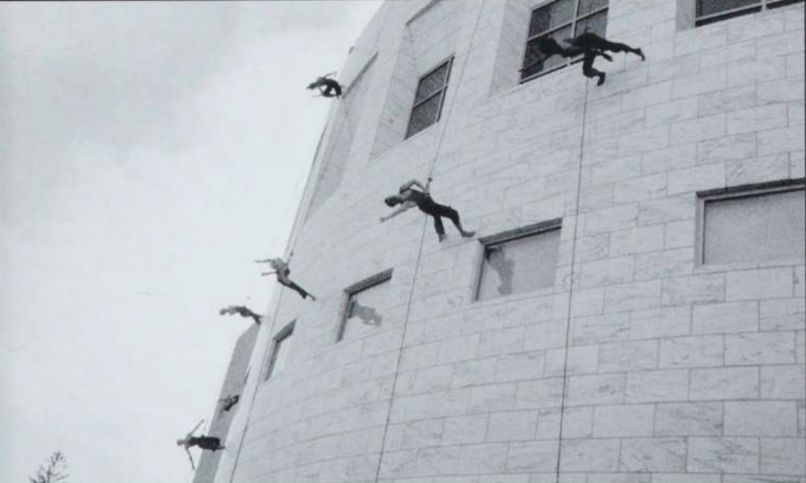 dancers suspended from ropes perform on the outer wall of Davis Family Library at the building dedication in 2004