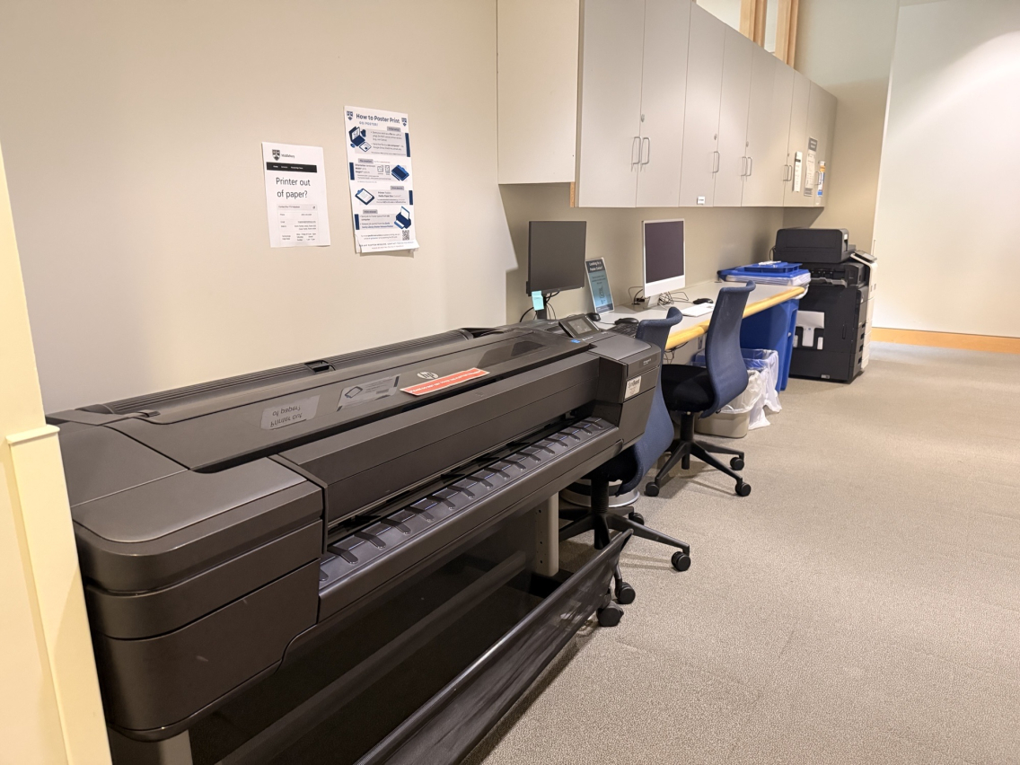 Photo of a large poster printer, two computers, and copy machine