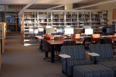 room with armchairs, tables and chairs, library stacks, and books
