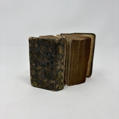 embroidered-binding book standing upright with pages partially splayed, showing unusual structure of two books bound together with three boards