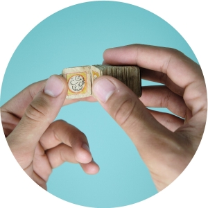 Hands holding a tiny Qur'an open against a blue background