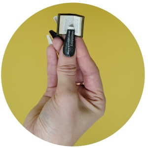 Hand holding tiny copy of Dialoghi against a yellow background.