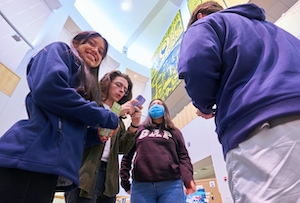 students in library atrium, one student smiling at camera