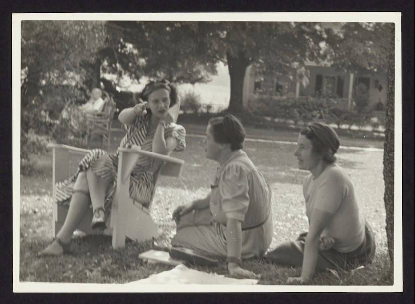 Bread Loaf Writers' Conference attendees chatting seated on lawn with cigarette-holding attendee gesturing toward camera seated in Adirondack chair