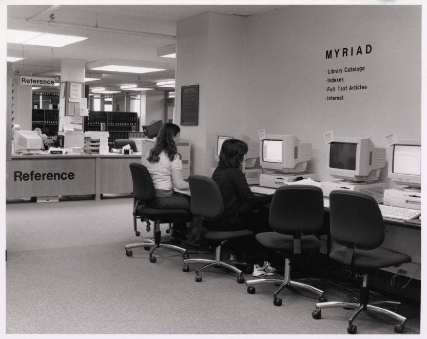 students sitting in front of computers with a sign stating "myriad"