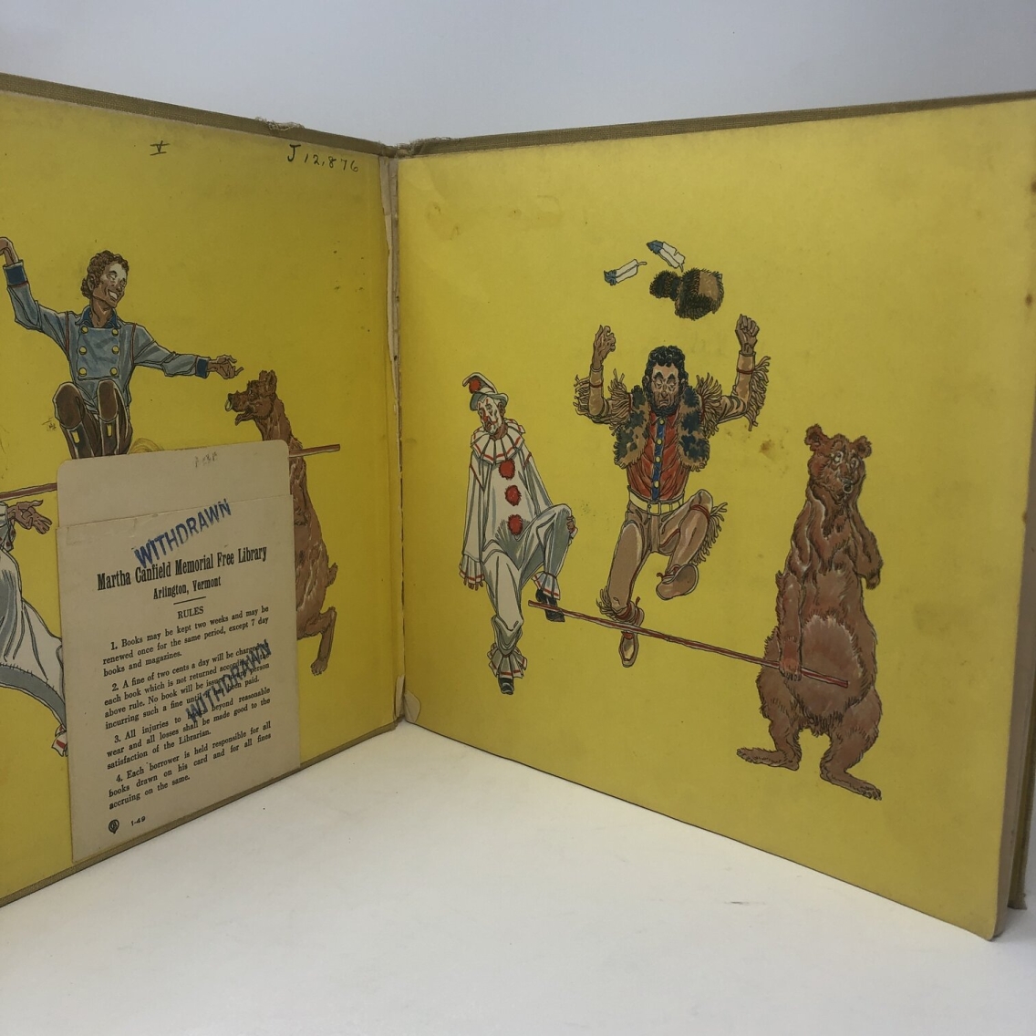 Photograph of the inside of Sam Patch by Arna Bontemps. The pages are yellow with what looks like circus characters mid-performance. There is a library book pocket from the Martha Canfield Memorial Free Library in Arlington, Vermont, stamped twice with the word "withdrawn."