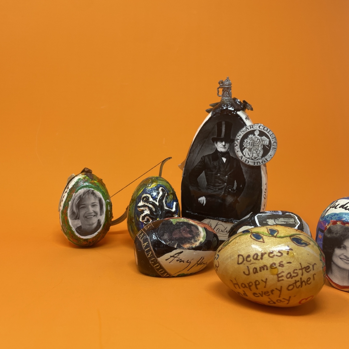 Seven wooden eggs painted and decorated by Nancy Willard, against an orange background.
