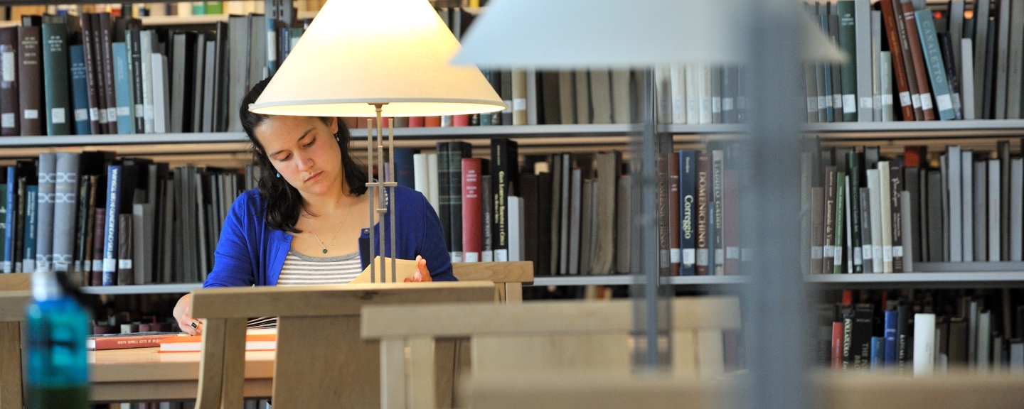 Female student studying at table in library, books in background