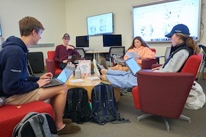 Four students with laptops sitting in a circle.