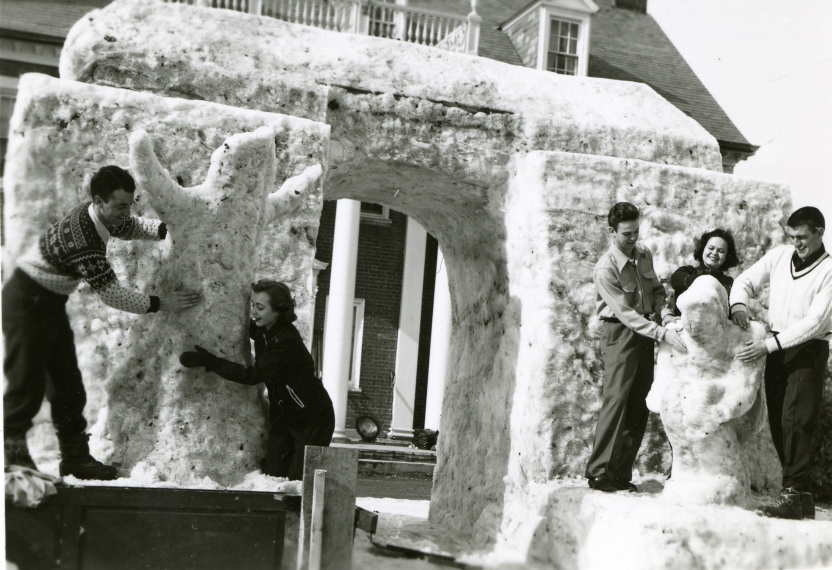 group of students constructs snow sculpture of archway with figures in front of Centeno House