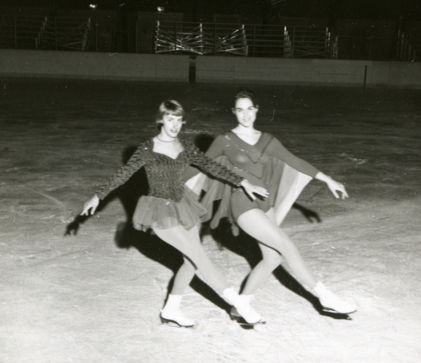 two students in costume posing with lifted leg on ice rink