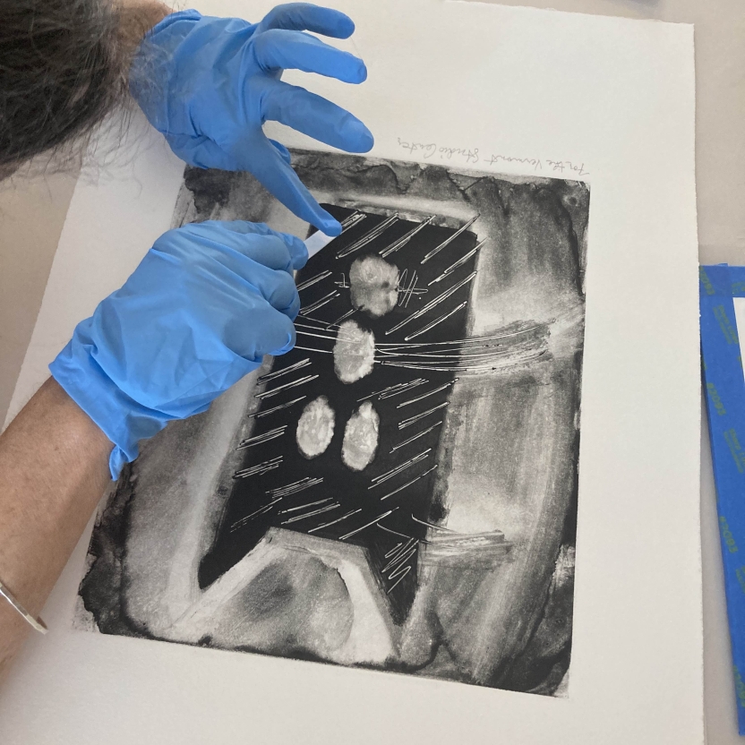 Hands with nitrile gloves performing preservation tests on an art print