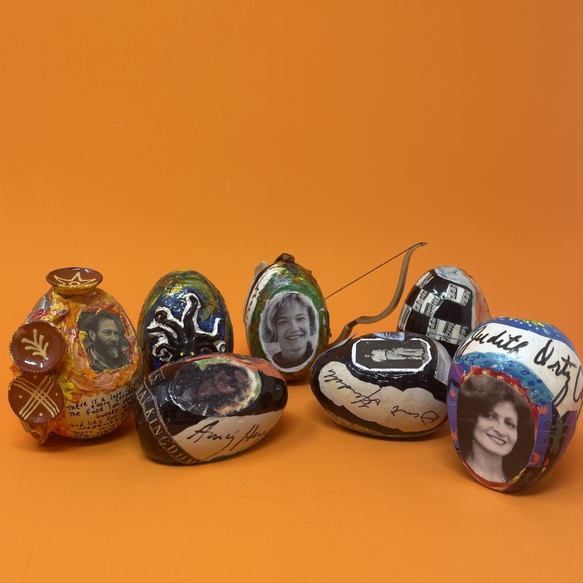 Eight decorated and painted wooden eggs against an orange background.
