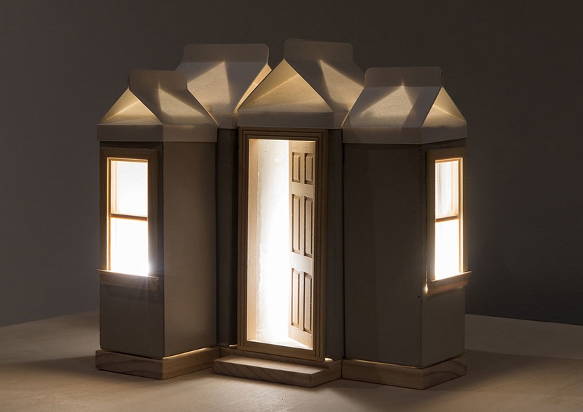 a small scale house with the front door open and warm light emanating from the door and windows