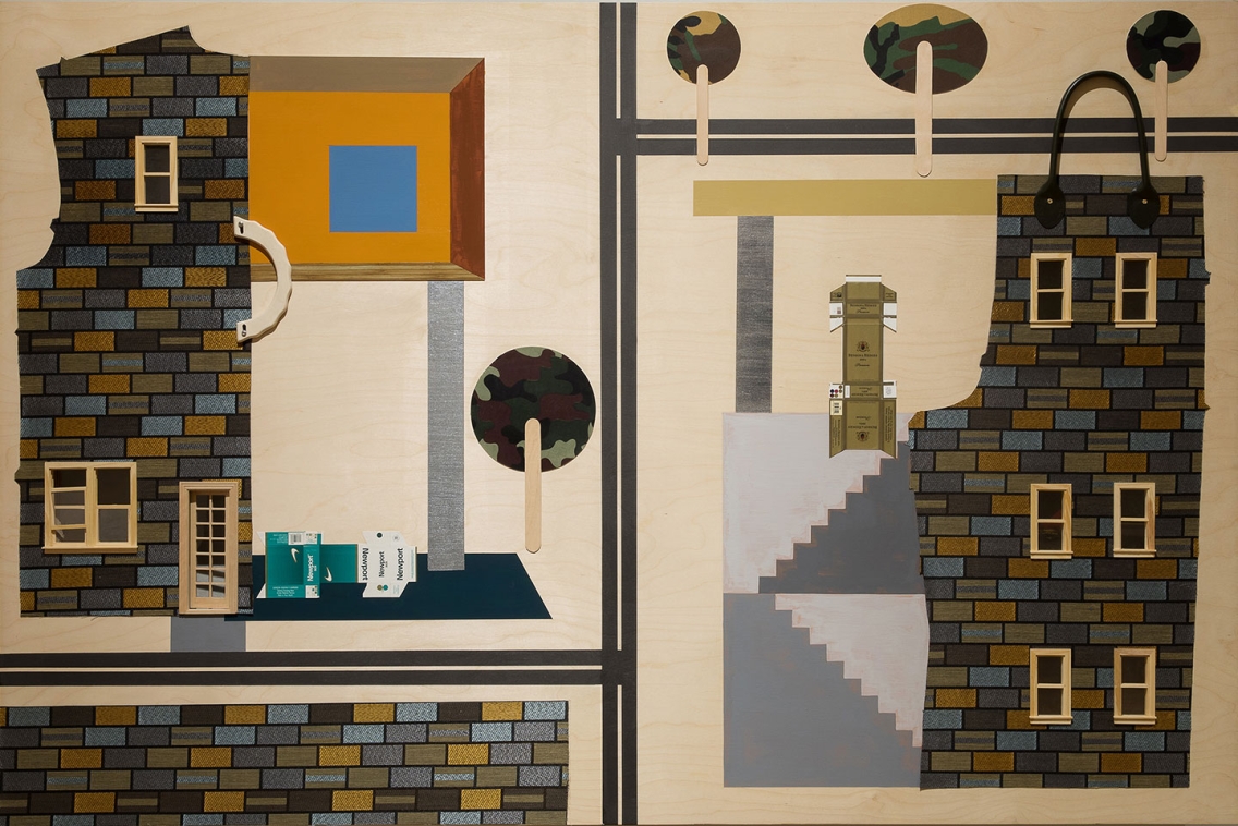 a light wood panel adorned with fabric, paper, and paint to suggest brick buildings and urban landscapes