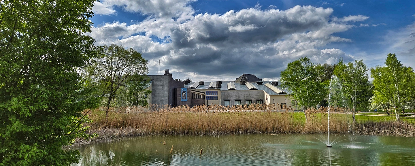 view of the Mahaney Arts Center and the Museum from across the pond on a sunny day