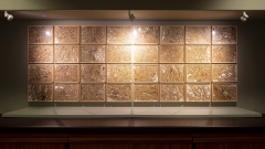 a grid of 32 framed collections of winter grasses mounted on a wall