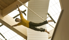 a human figure in a flying posture wears a yellow shirt and brown pants which appear to flap in the wind