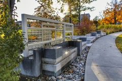 a mostly concrete structure with painted steel, aluminum, and copper elements and plantings