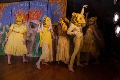 players dressed primarily in yellow wear large full-head lion masks and prowl on stage