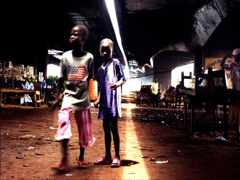 two black children stand in the middle of a city street at night