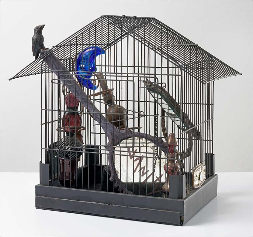 an assemblage of items -- including a mirror, a bird, a blue glass moon, and other trinkets -- in a wire bird cage