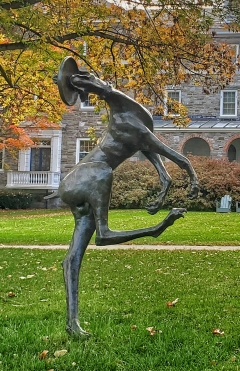 a large, slender, bronze Great Dane jumps playfully to catch a frisbee
