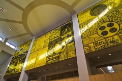 a large three-panel mural with black writing and glyphs etched onto a yellow background