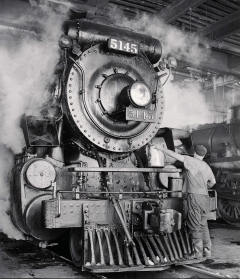 black and white image of a locomotive with steam billowing all around it