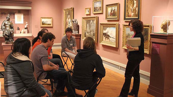 A faculty member teaches students about the art work in the Cerf Gallery.