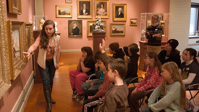 Elementary students listen to a guide describing art work in the Cerf Gallery.