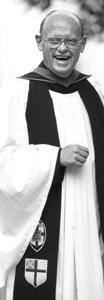 black and white photo of a smiling Rev. Charlie Scott in academic robe and stole