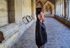 Photo of Carol Lin standing alone in a stone hallway