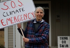 Woman holding a sign with the words SOS climate emergency