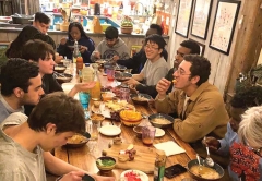 Students gather around a large table to eat dinner