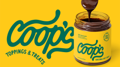 Coop's Toppings and Treats. A spoon poised over an open jar of chocolate sauce 