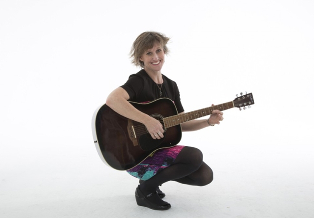 Portrait of Aimee Young Hopkins holding an acoustic guitar