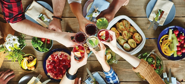 hands raising glasses around a table spread with food