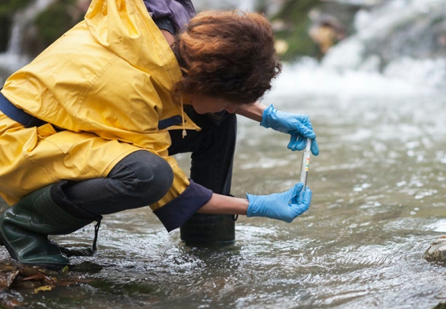 Person taking a water sample from a river