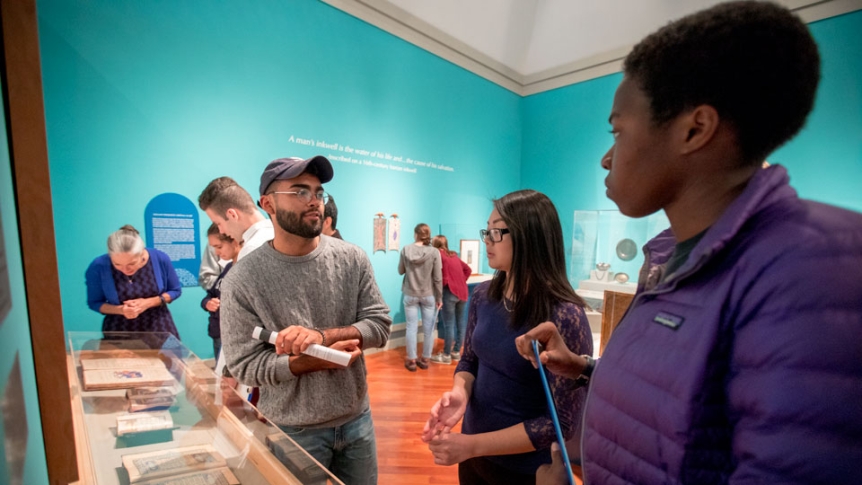Two students and their professor discuss research projects in the Middlebury Museum of Art.