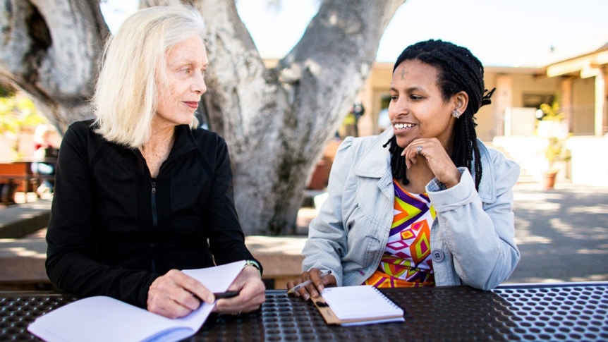 Professor Andrea Olsen sits outdoors with a student participant of 10 x 10 at MIIS.