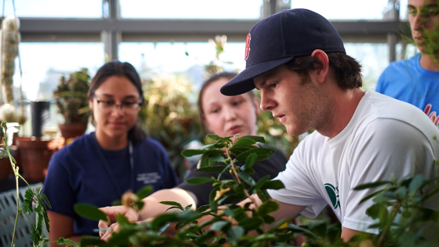 A student participates in class in the College’s greenhouse.