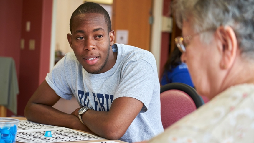 A male student visits a local nursing home to visit with elderly friends.